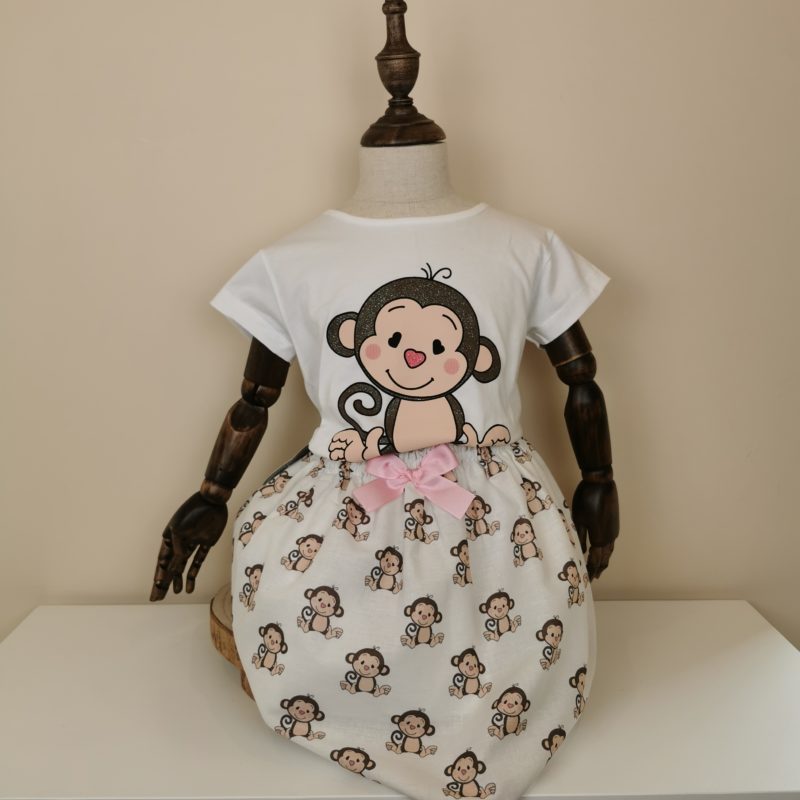 Conjunto super dulce, compuesto de camiseta blanca con monito en marrón con glitter. Falda con estampado de monitos,goma cintura y lazo rosa.